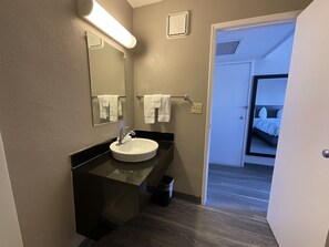 Un baño moderno con lavamanos, espejo y toallero.