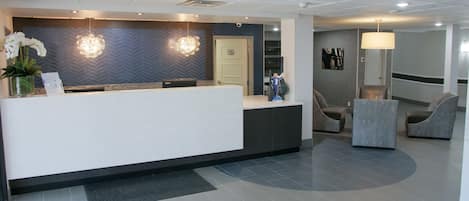 A reception area with a white counter, two wall-mounted light fixtures, and a door to a waiting area.
