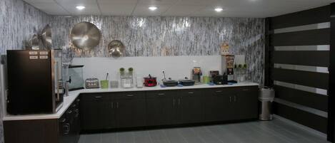 A modern kitchen with dark cabinets, a stainless steel refrigerator, and a marble backsplash.