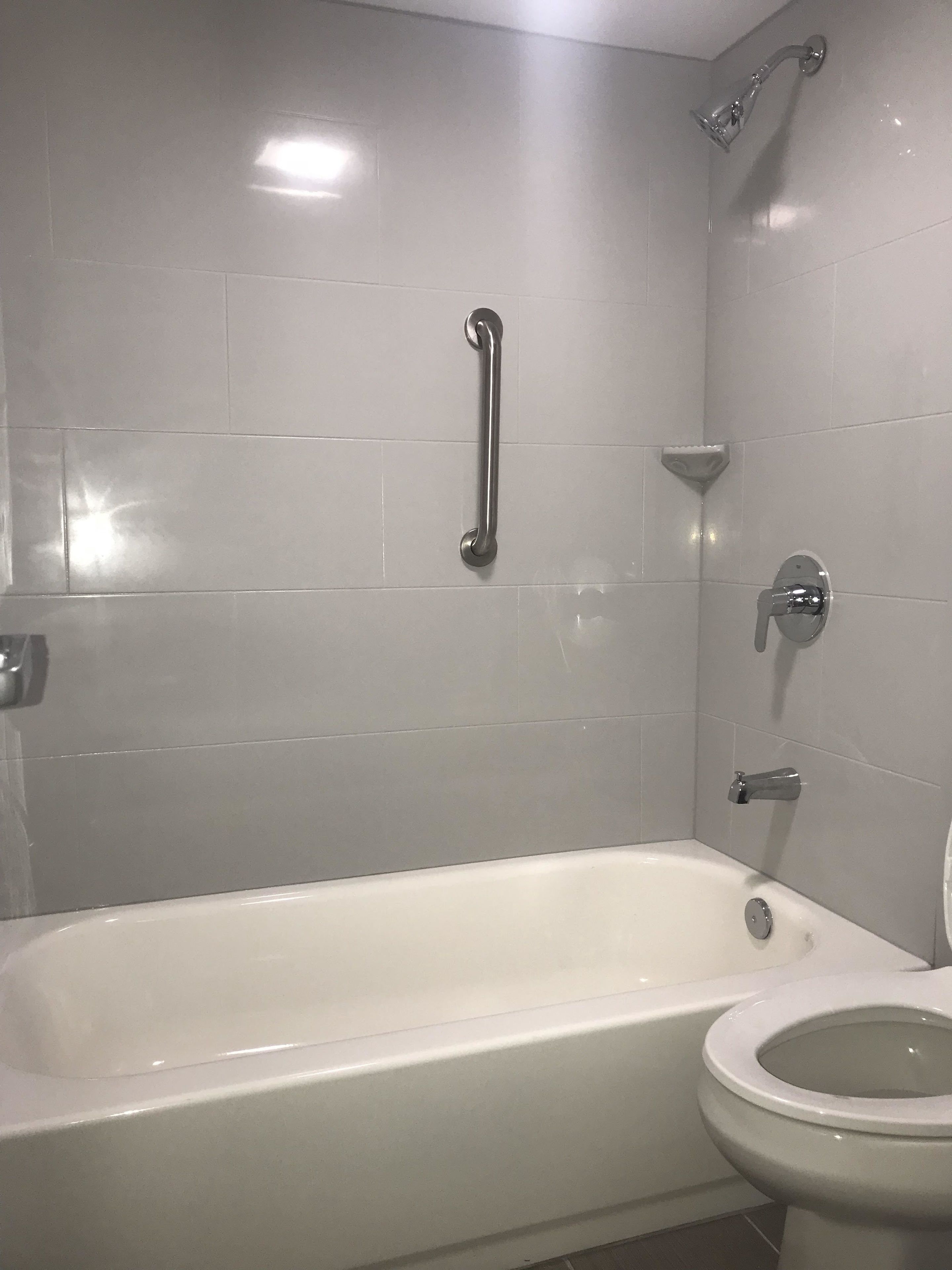 Et badeværelse med badekar, toilet og bruser.