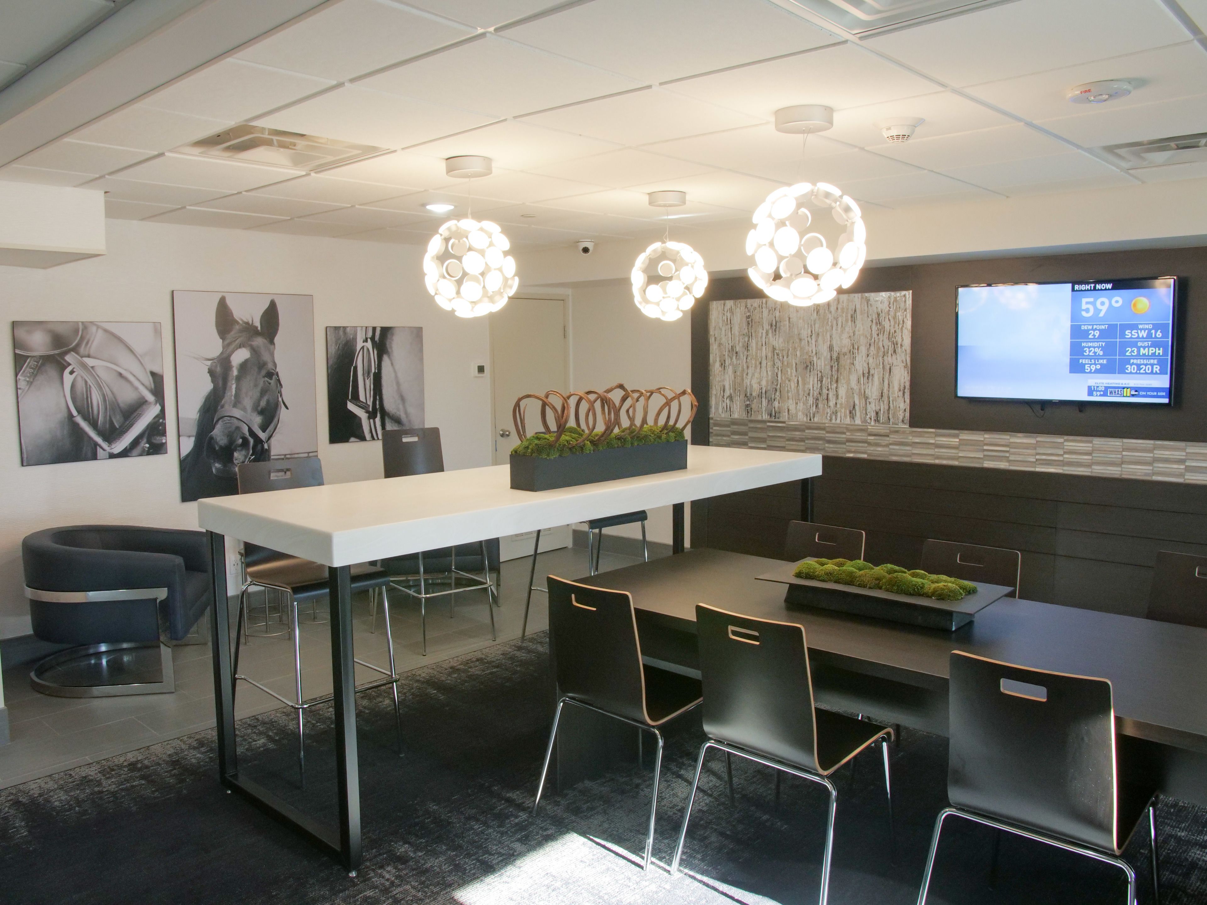 A modern conference room with a white table, black chairs, and decorative lighting.