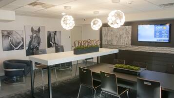 A modern conference room with a white table, black chairs, and decorative lighting.