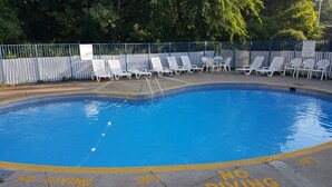 Una piscina con sillas de descanso blancas y una valla.