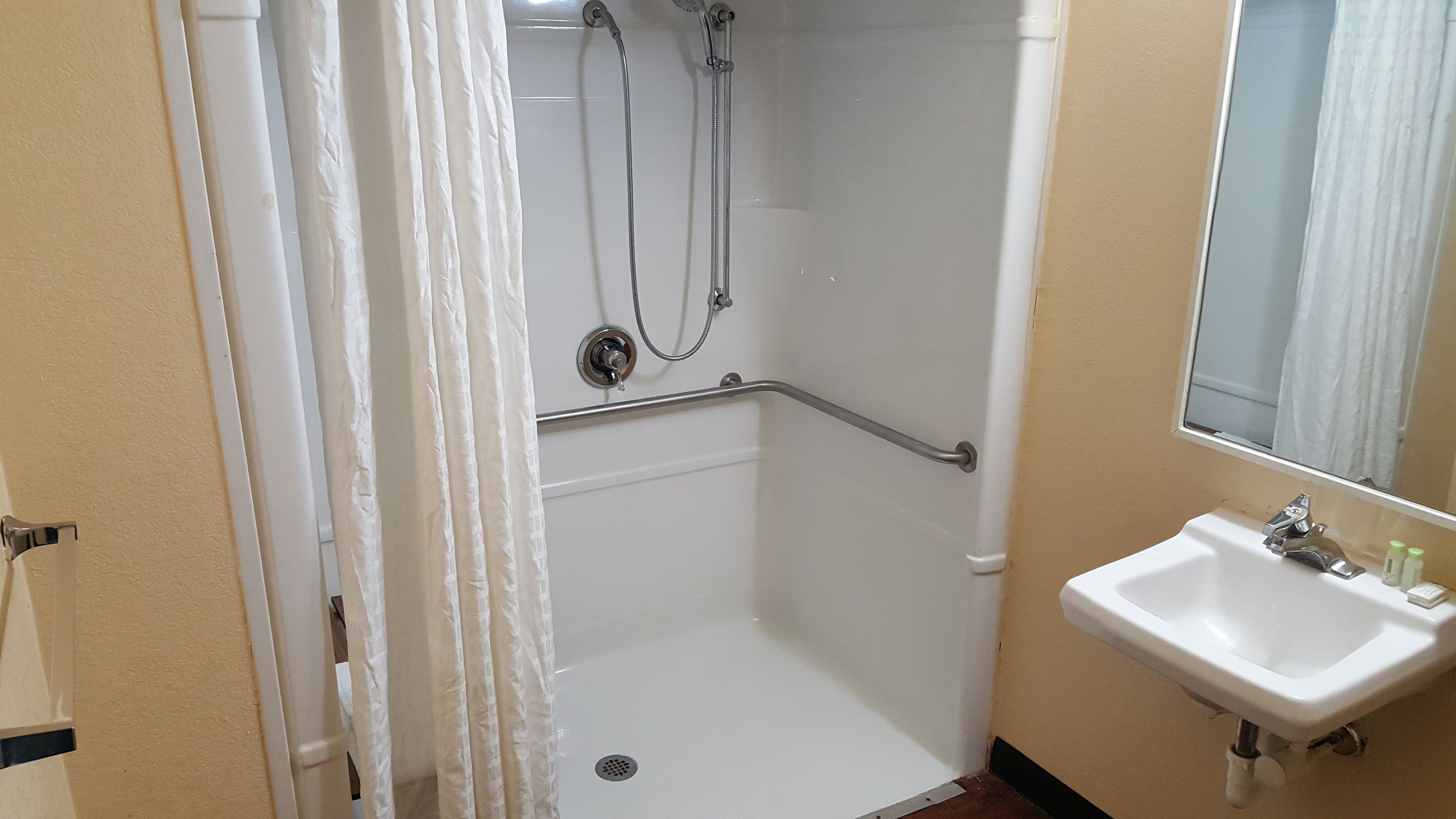 A bathroom with a shower, a sink, and a mirror.
