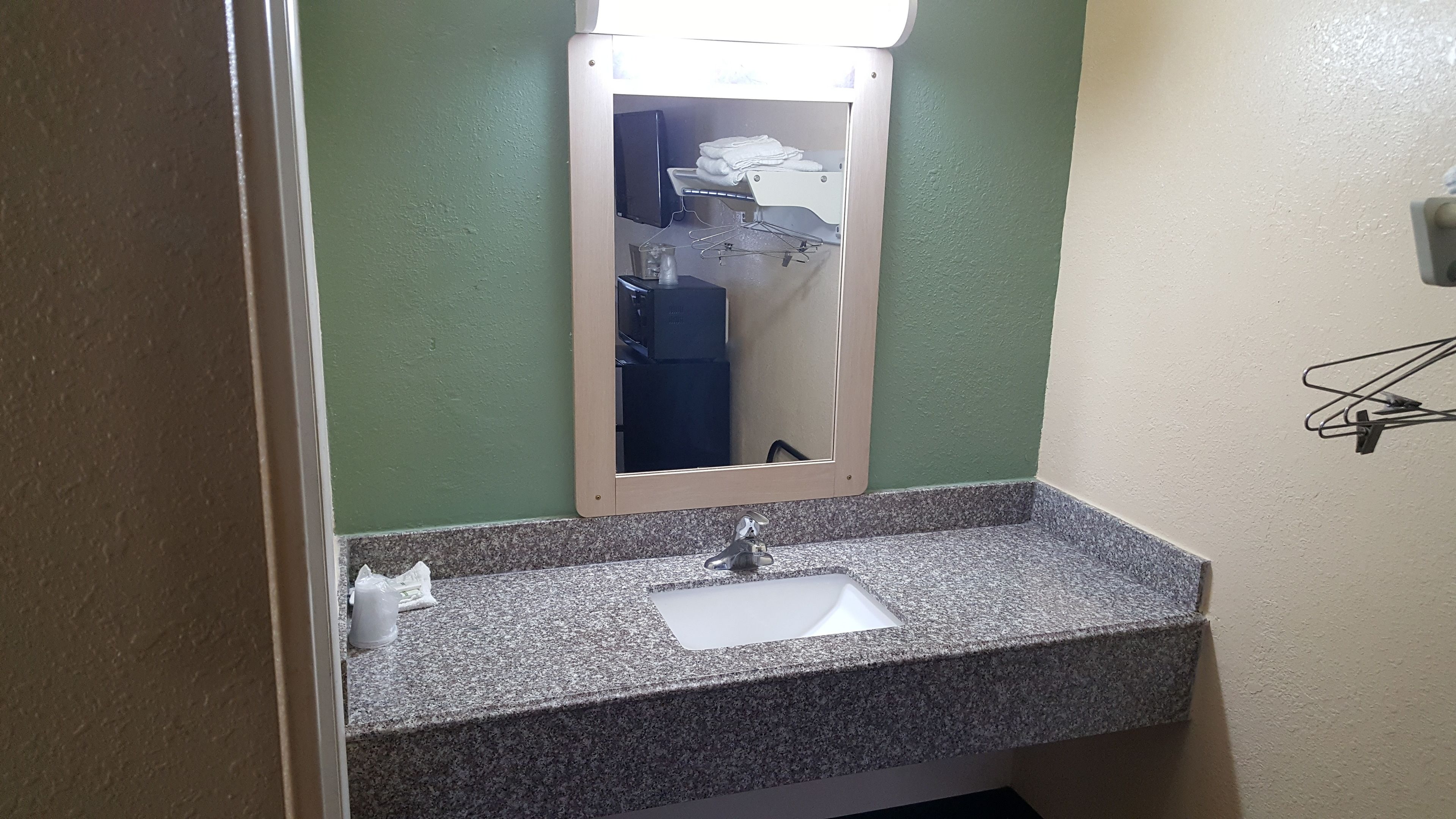Baño con lavamanos de encimera de granito, espejo y toallero.