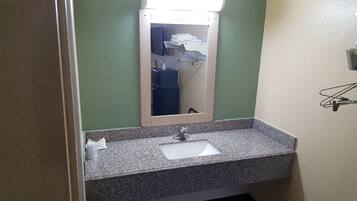 Baño con lavamanos de encimera de granito, espejo y toallero.