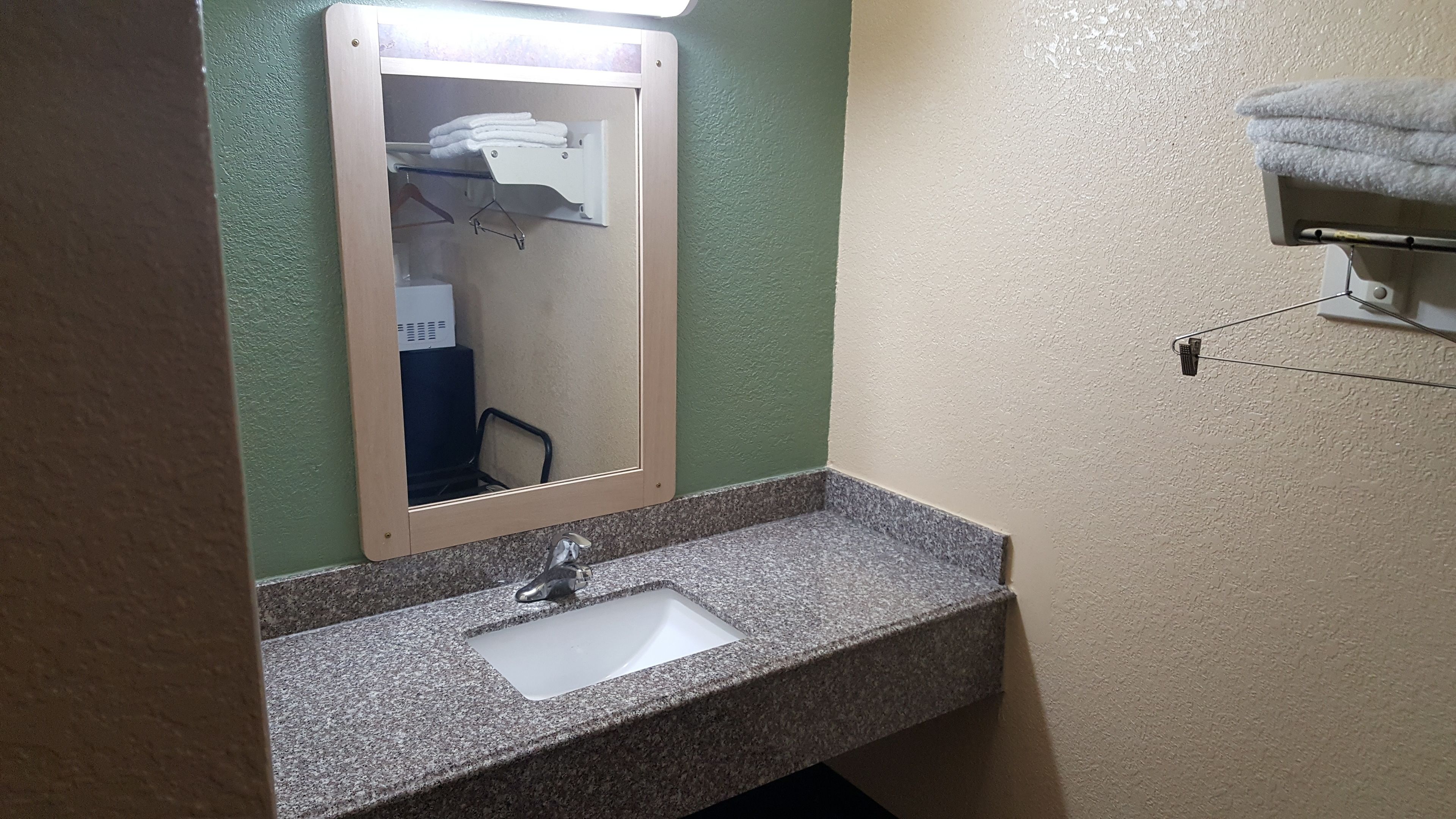 Un bagno con lavabo in granito, uno specchio e un porta asciugamani.