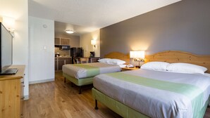 A hotel room with two beds, a desk, a chair, and a kitchenette in the background. - Studio 6 Tempe, AZ (Tempe)