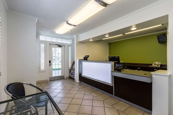A reception area with a glass partition, a reception desk, and a green wall.