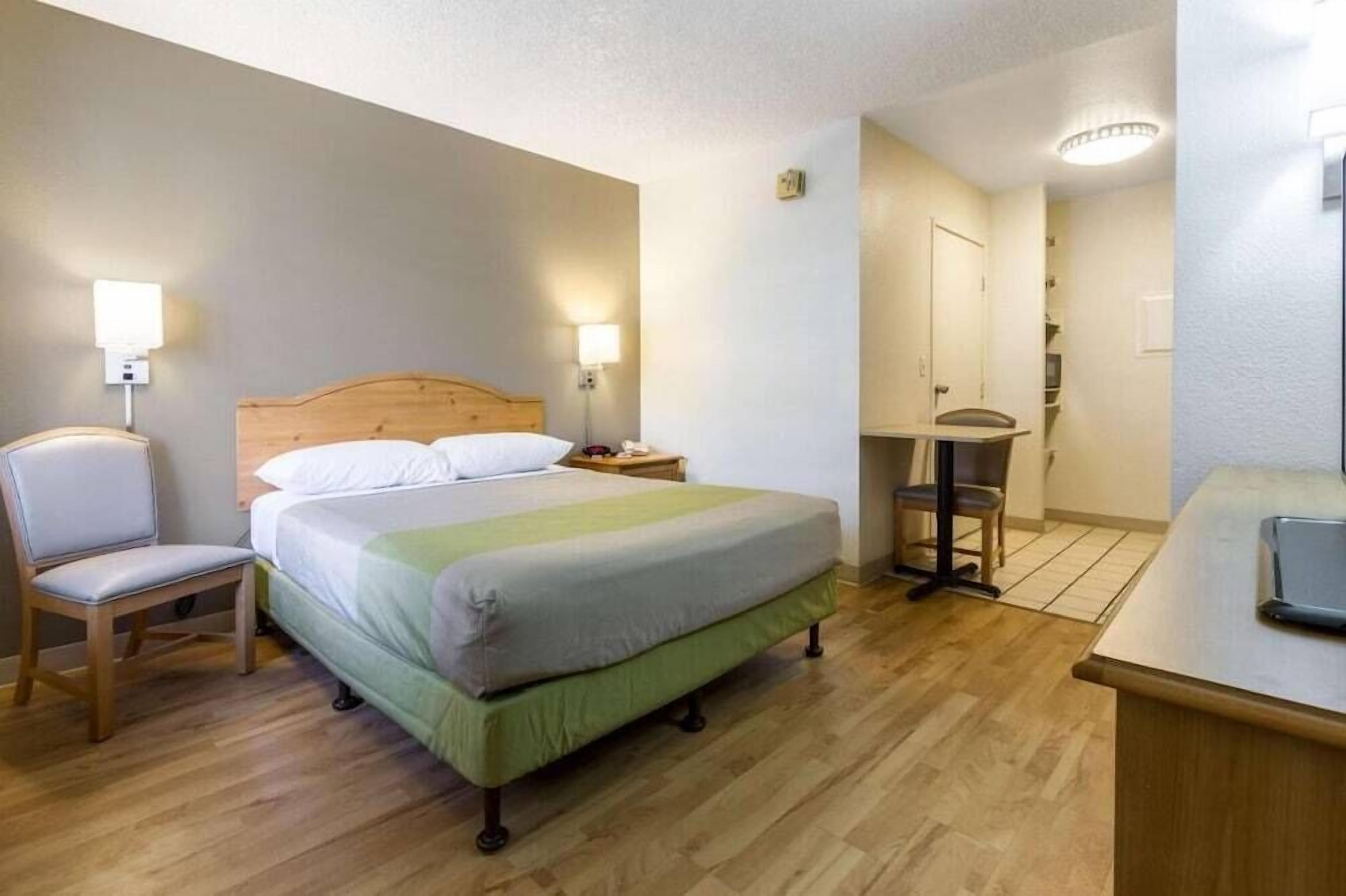 Et hotelværelse med en seng, en stol, et skrivebord og et lille bord.