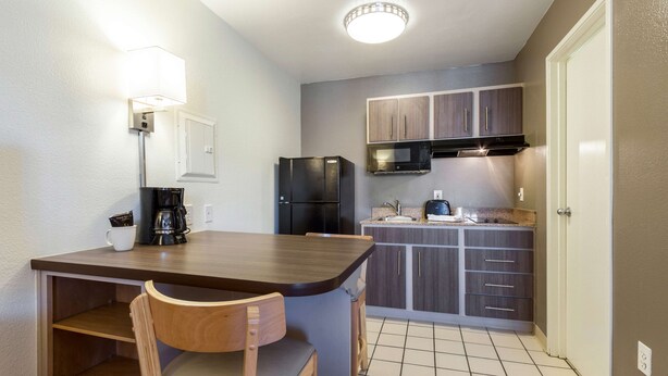 A compact kitchen with a dining area, a refrigerator, a microwave, and a coffee maker. - Studio 6 Tempe, AZ (Tempe)