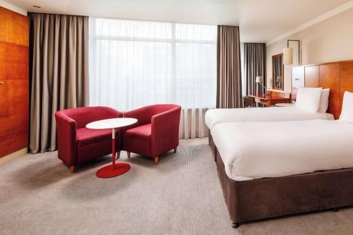 Hotellihuone, jossa on sänky, työpöytä, tuoli ja pieni pöytä.