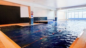 An indoor swimming pool with lanes, a diving board, and a no diving sign.