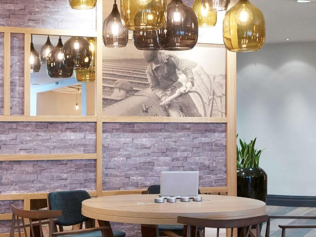 A conference room with a round table, chairs, a laptop, and a large framed photograph on the wall.