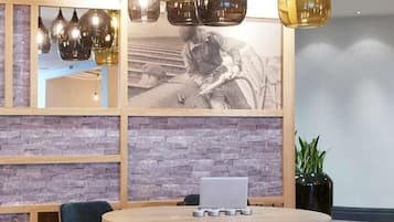A conference room with a round table, chairs, a laptop, and a large framed photograph on the wall.