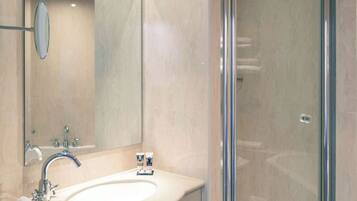A modern bathroom with a large sink, a mirror, and a glass shower enclosure.