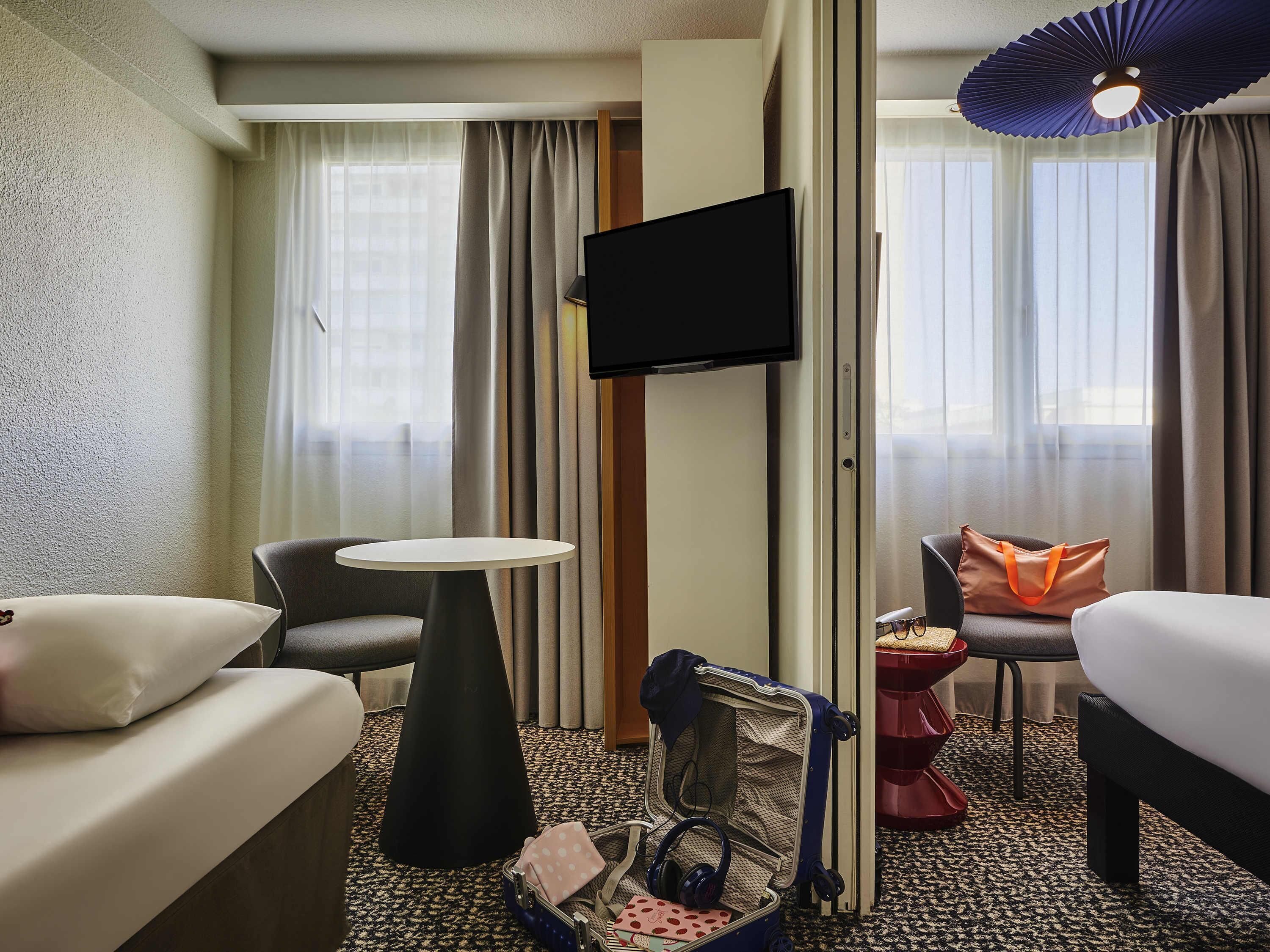 Een hotelkamer met een bed, een bank, een kleine tafel, een televisie en een koffer.