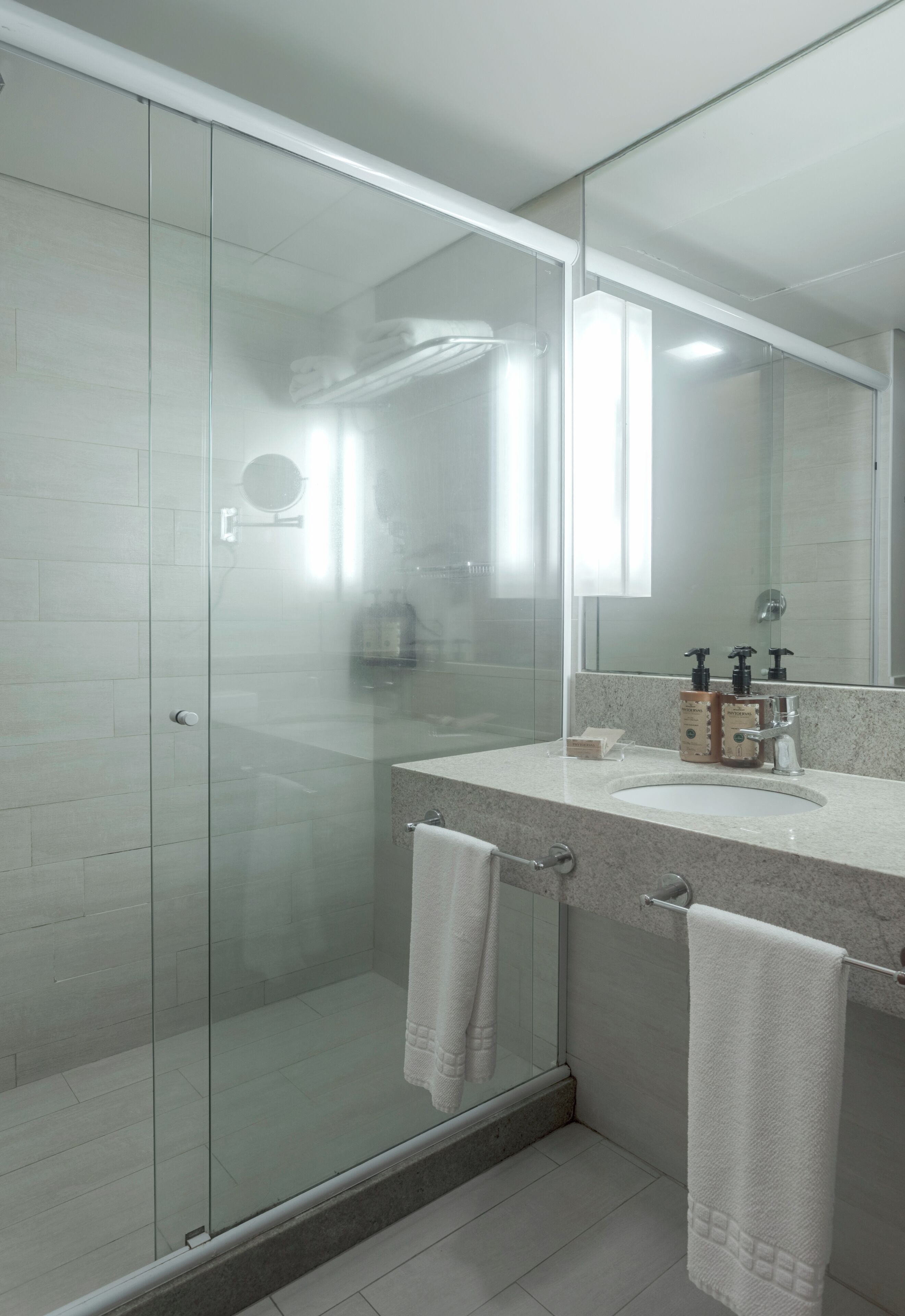 A modern bathroom with a glass shower enclosure, a vanity with a sink, and a large mirror.