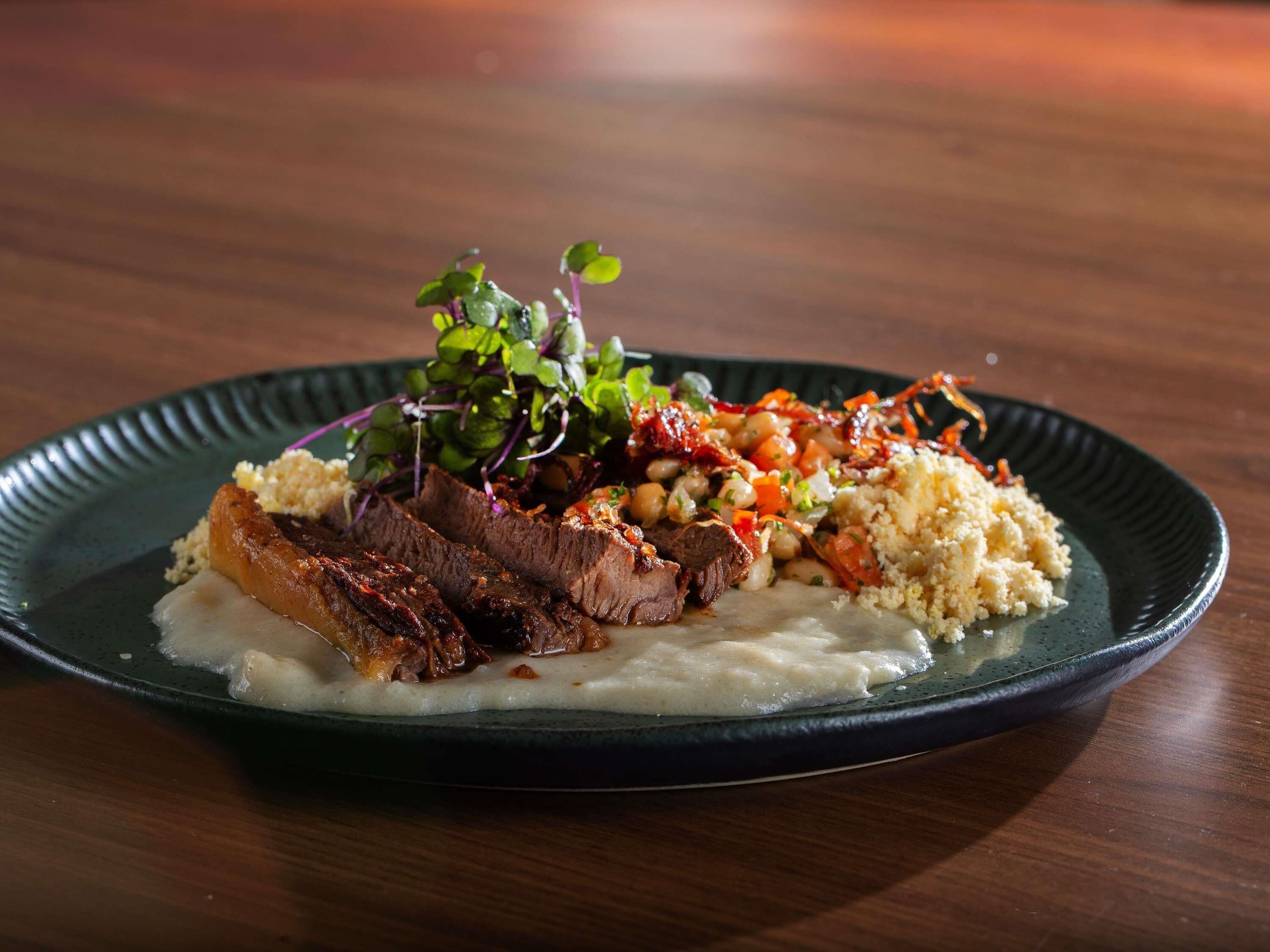 Un plato con carne, cuscús y una ensalada.