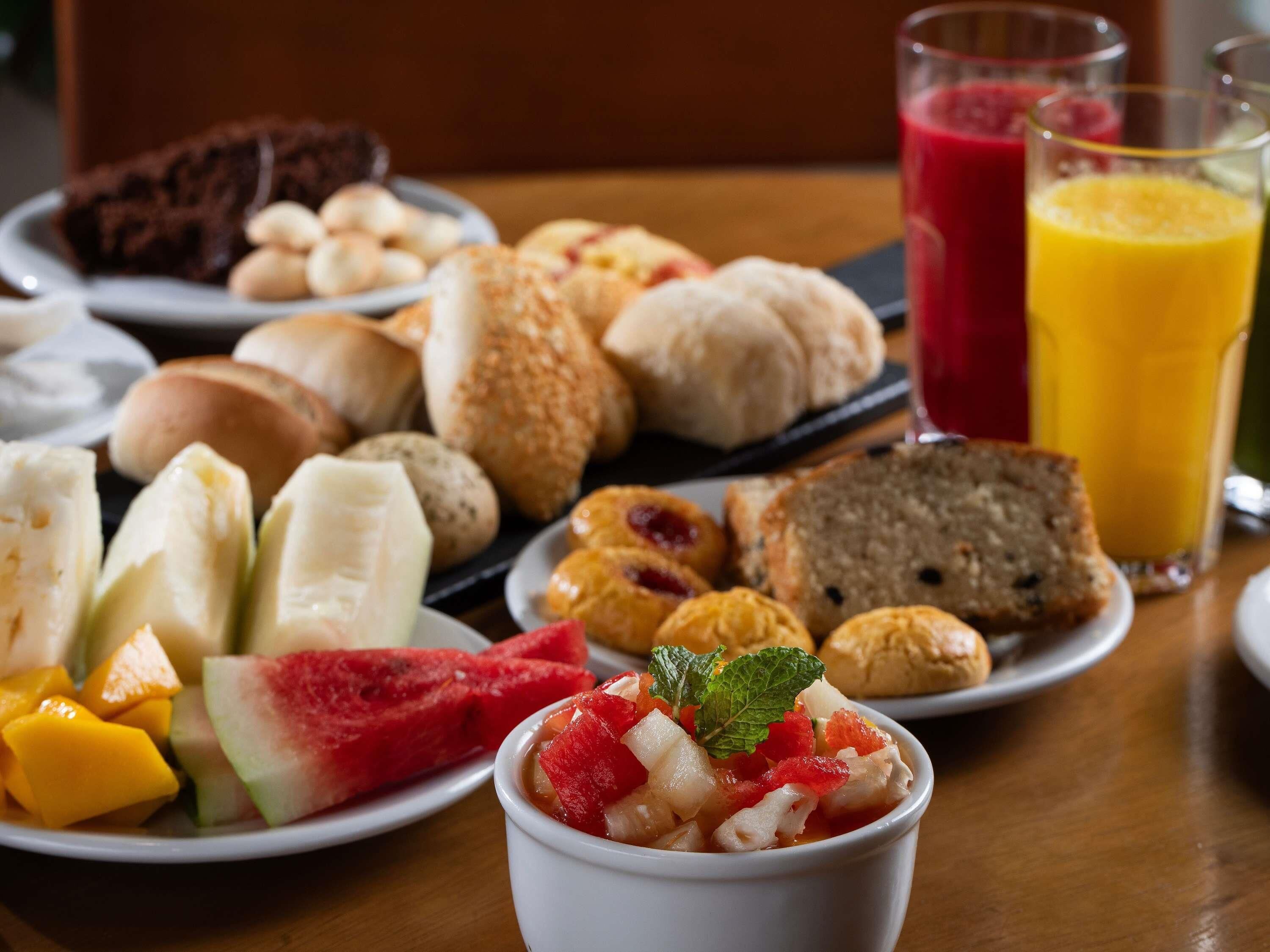 A breakfast spread with various pastries, fruits, and juices on a wooden table.