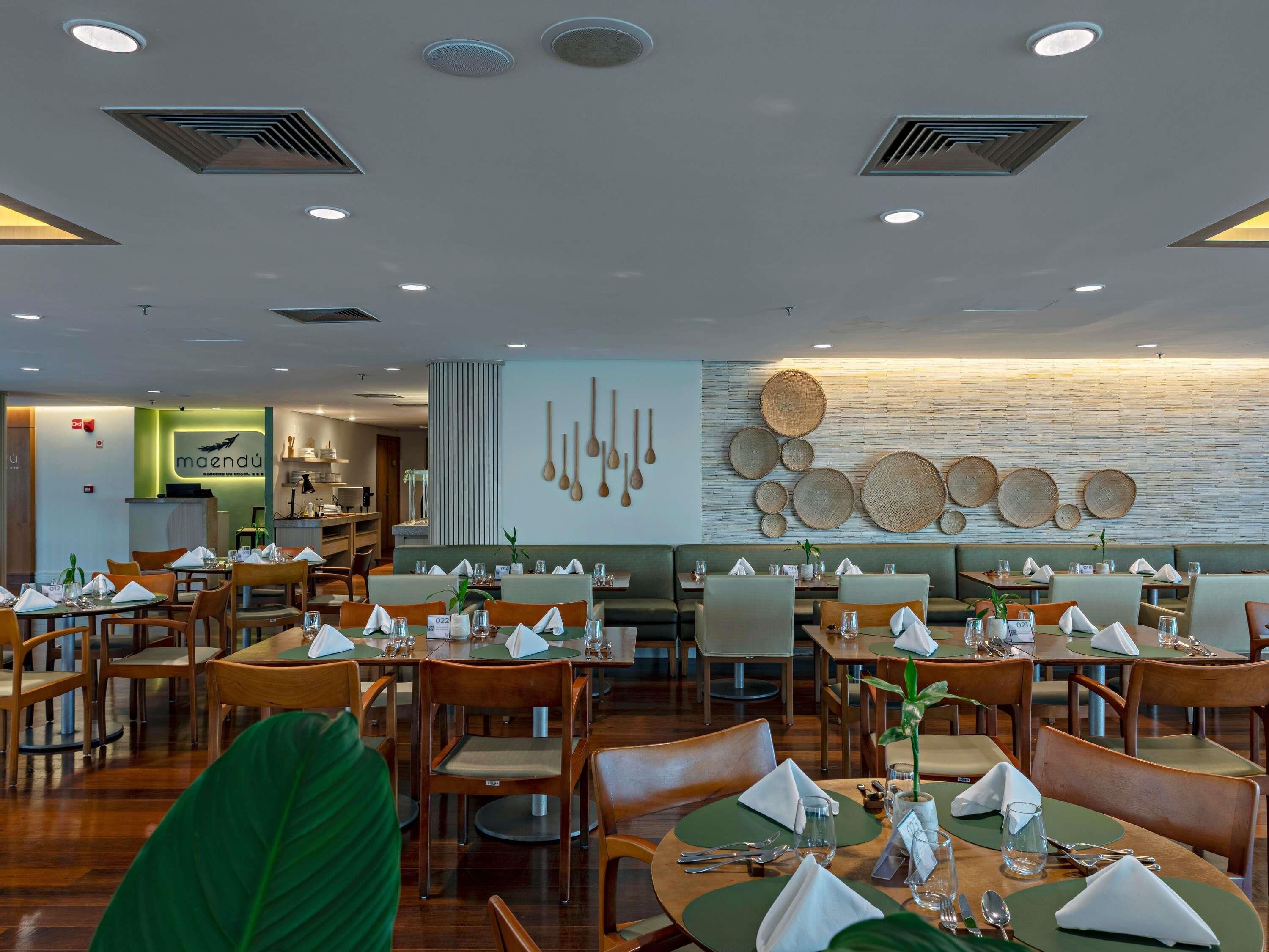 A restaurant with round tables, wooden chairs, and a wall decorated with woven baskets.