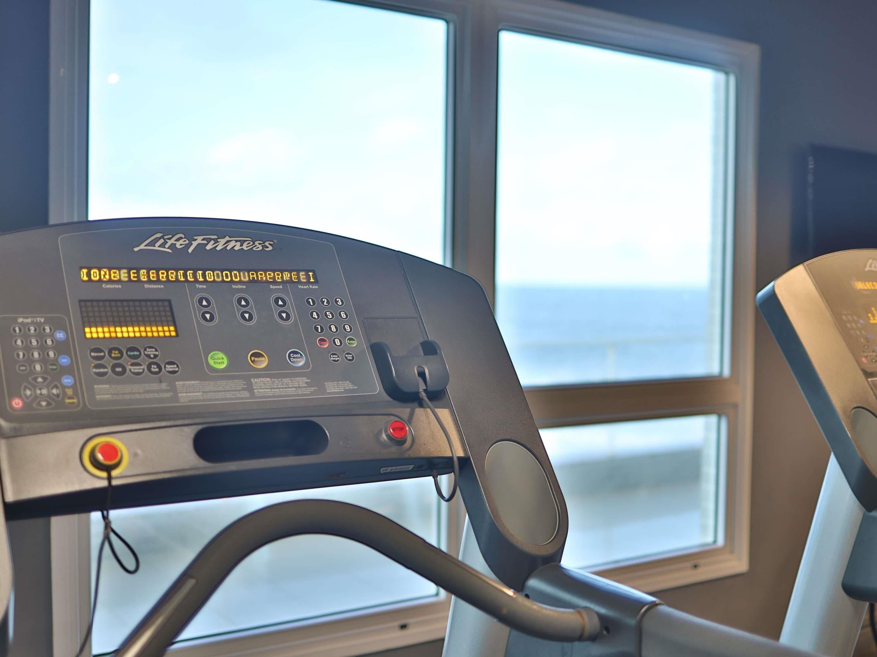 A stationary bike with a digital display, control panel, and a window in the background.