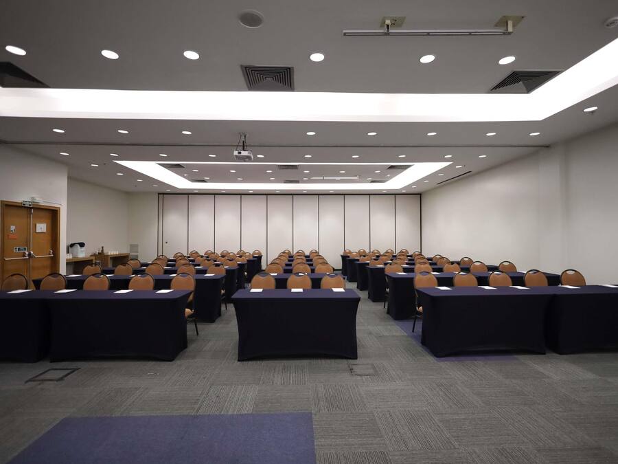 A conference room with rows of tables and chairs, a projector, and a door labeled 'GADA 1'.