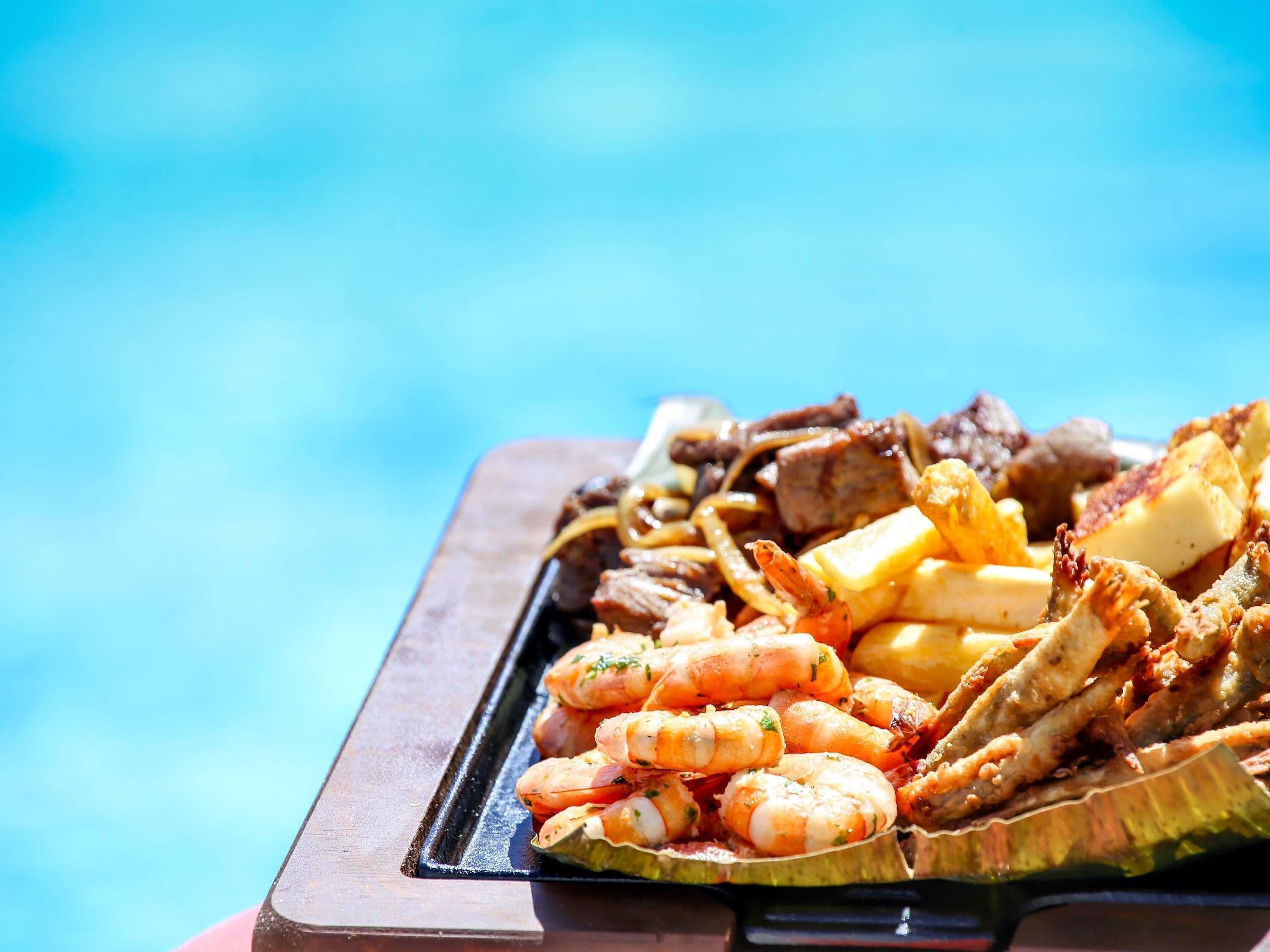 Bandeja de mariscos que incluye camarones, vieiras y pescado, probablemente preparada para una comida.