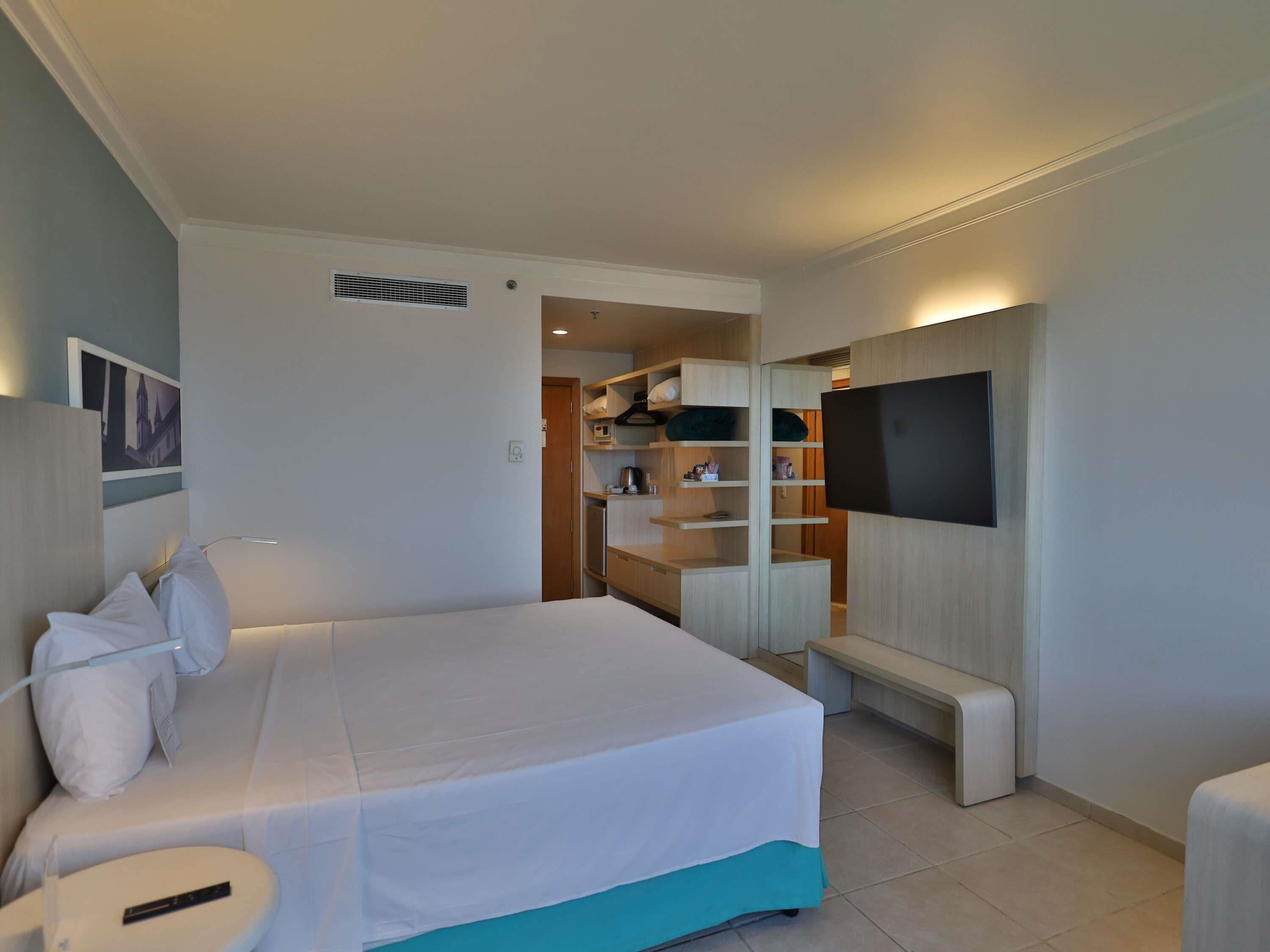 Une chambre d’hôtel équipée d’un lit, d’une télévision, d’une banquette et d’une kitchenette.