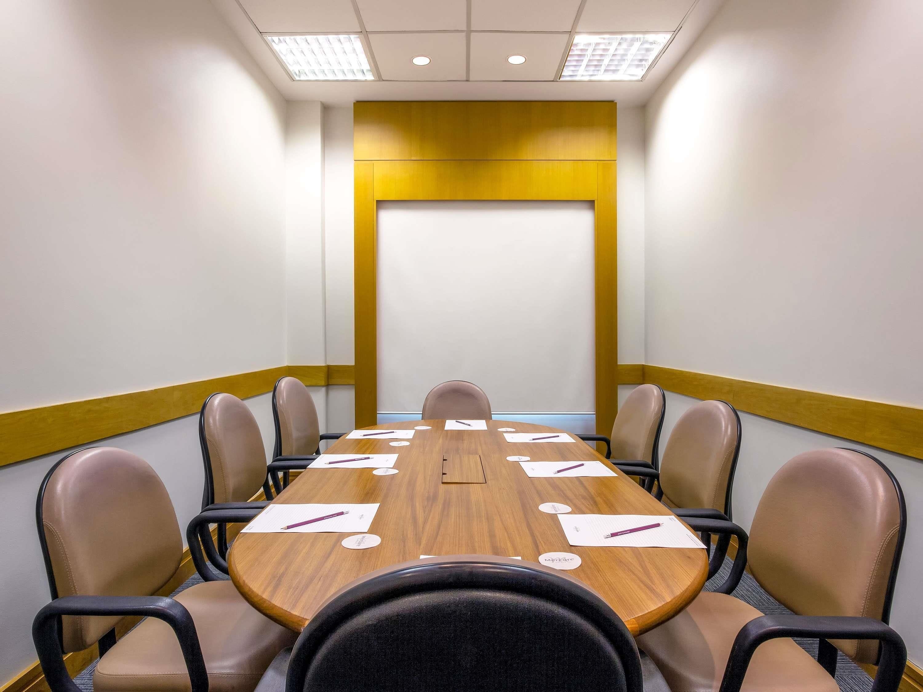 Un salón de conferencias con una larga mesa, seis sillas y una pizarra.