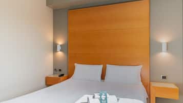 Ein Hotelzimmer mit einem Holzkopfteil, weißer Bettwäsche und zwei Nachttischlampen.