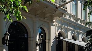 A building with classical architecture, featuring arched doorways and a red carpet leading to the entrance.