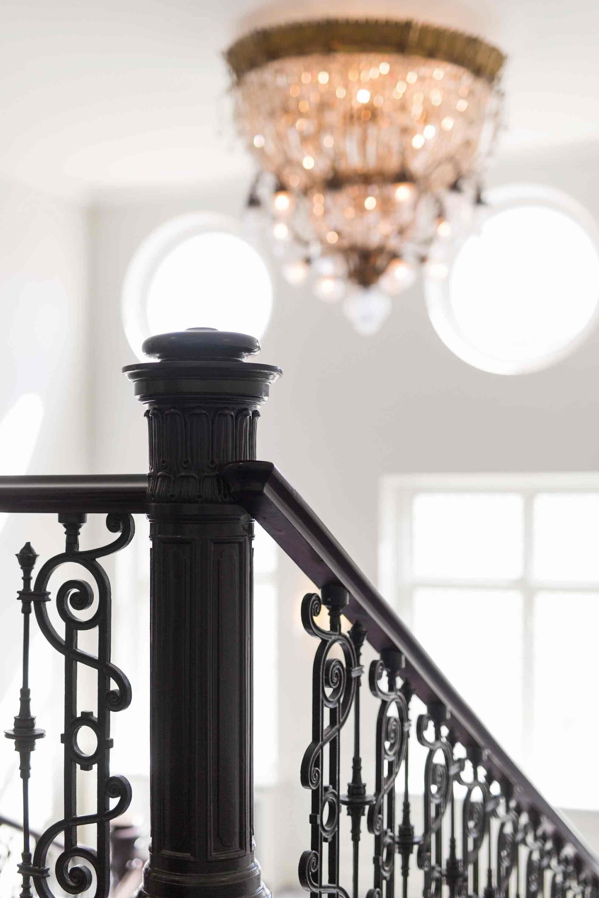 Una escalera con barandillas de metal negras y ornamentadas y una columna de estilo clásico.