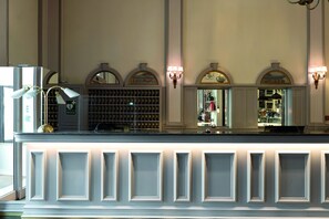 A hotel reception area with a counter, wall-mounted lamps, and a display of items behind the counter. - Elite Hotel Mollberg (Helsingborg)