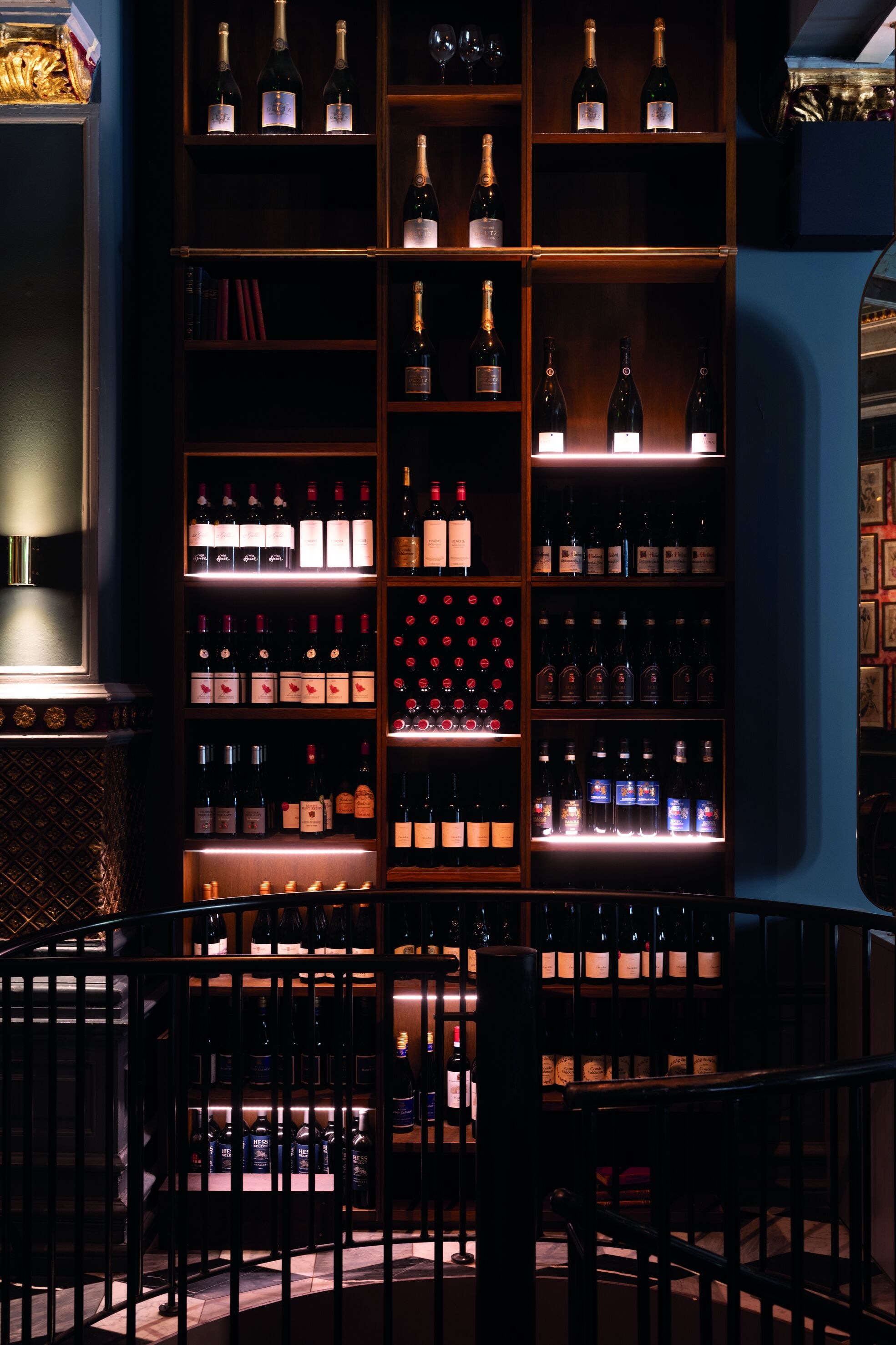 A wine cellar with shelves of wine bottles and a selection of books.