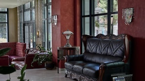 A spacious lobby with a leather sofa, a red armchair, and a potted plant. - Delphi Art Hotel (Athens)