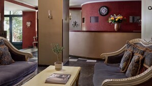 A hotel lobby with a red accent wall, a clock, and a vase of flowers. - Delphi Art Hotel (Athens)