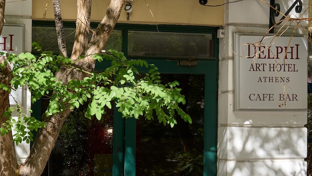 The exterior of the Delphi Art Hotel Athens Cafe Bar, featuring a green door and a signboard. - Delphi Art Hotel (Athens)