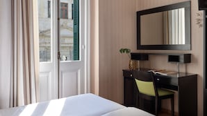 A hotel room with a bed, a desk with a chair, a large mirror, and a window with curtains. - Delphi Art Hotel (Athens)