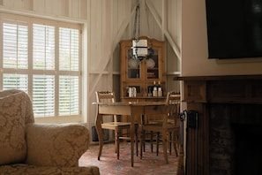 A room with a wooden dining table, chairs, a cabinet with dishes, and a fireplace. - Simpson House Inn (Santa Barbara)