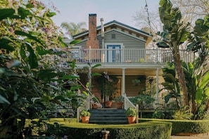 Une maison à deux étages avec un balcon, des plantes en pot et un jardin bien entretenu.