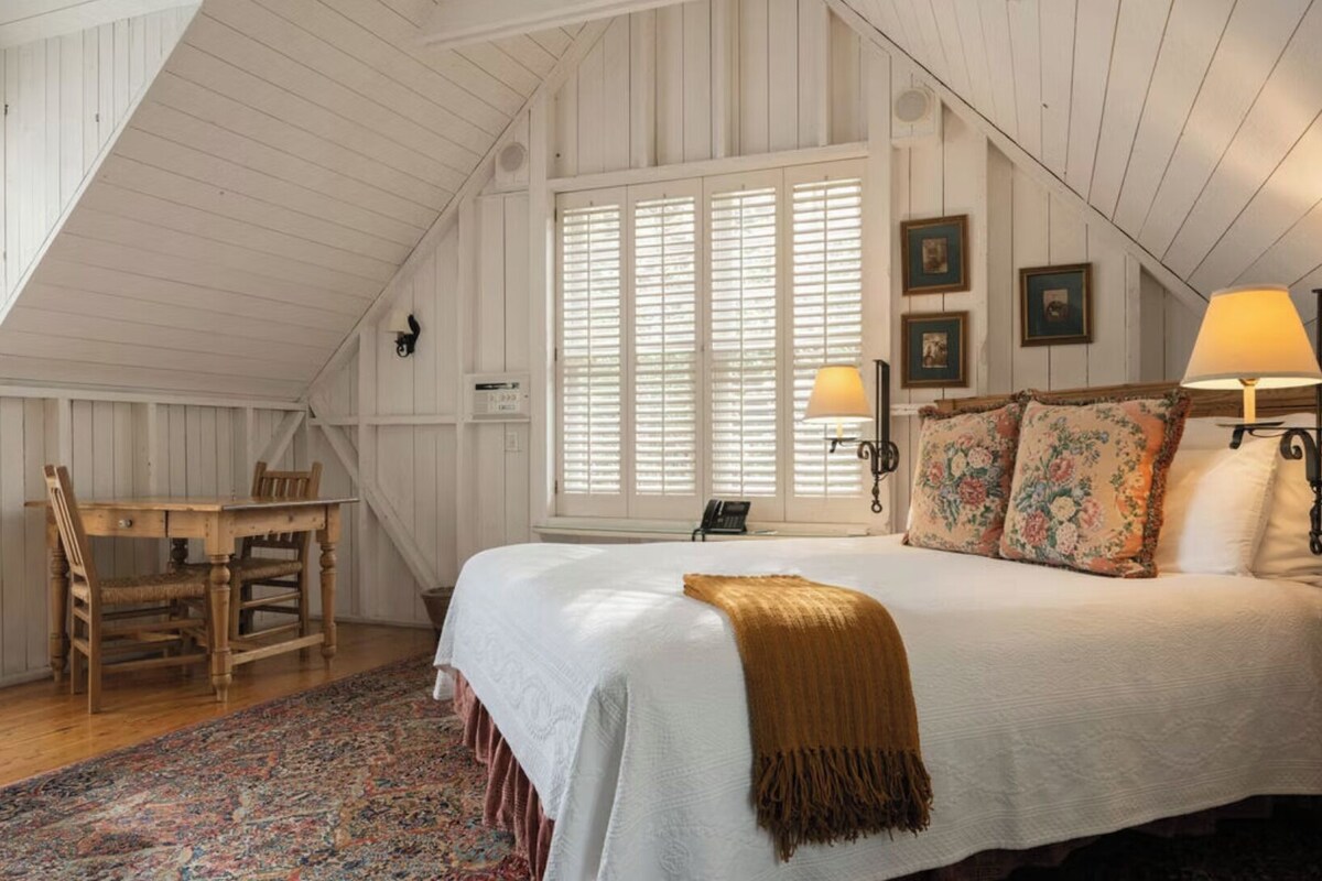 A bedroom with a large bed, a desk, and a chair.