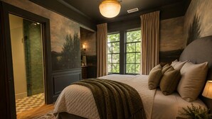 A bedroom with a large bed, a window with curtains, a nightstand with a lamp, and a door leading to a bathroom. - Simpson House Inn (Santa Barbara)