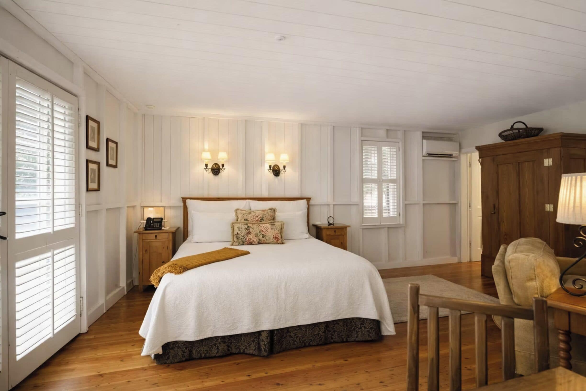 A bedroom with a large bed, two bedside tables, a wooden chair, and a wardrobe.