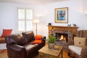 A living room with a leather sofa, a wooden coffee table, a fireplace, and a window with blinds.