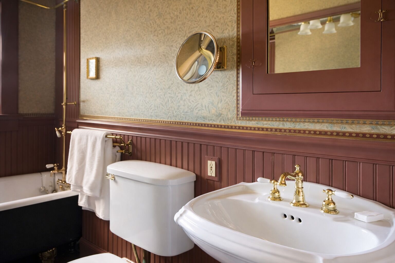 A bathroom with a bathtub, toilet, and sink, all with gold fixtures.