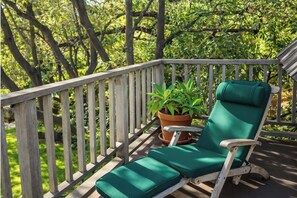 A wooden deck with a green cushioned chair and a potted plant.