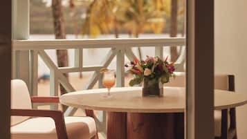 A round wooden table with a vase of flowers and a glass of orange drink.