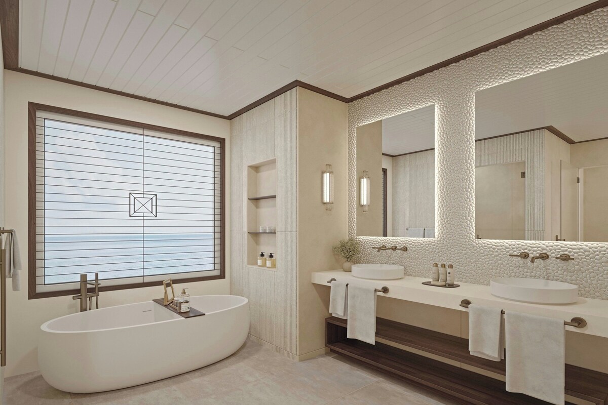 A modern bathroom with a freestanding bathtub, two sinks, and a large mirror.