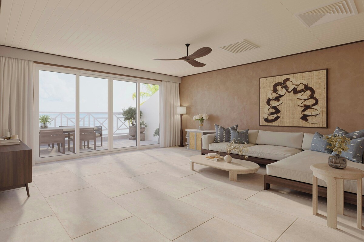 A spacious living room with a large sliding glass door leading to an outdoor area, a ceiling fan, and a modern sofa set.